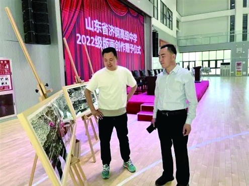 济钢高中校长、党委副书记桑胜旺(右)参观学生版画研学作品
